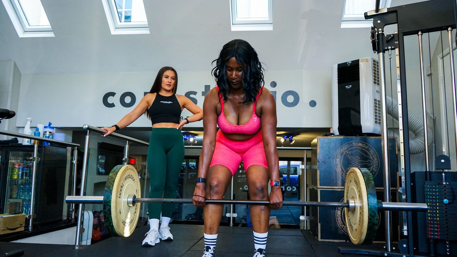 Two members lifting together beneath the Core Studio sign at the Blackheath studio